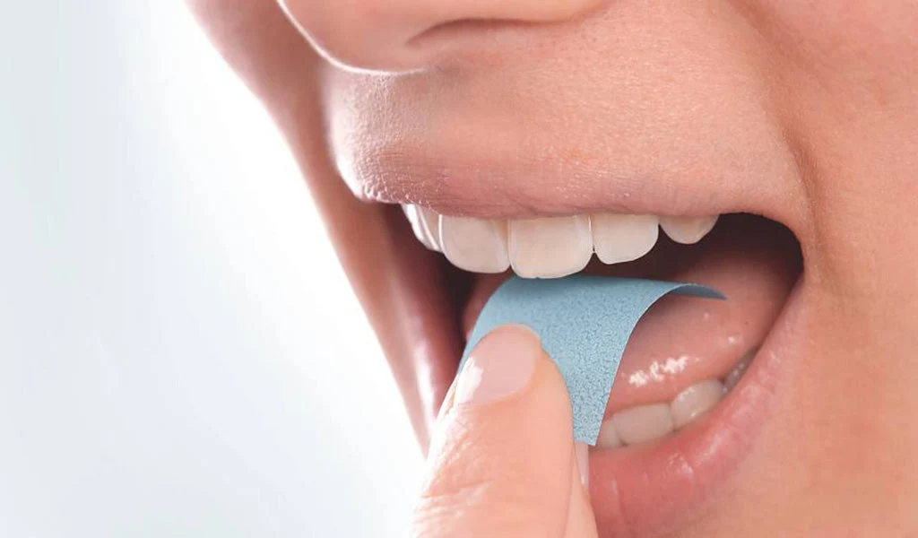 Person placing an oral dissolving film strip on the tongue